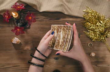 Tarot cards and hands of fortune teller on wooden table background.