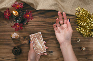 Tarot cards and hands of fortune teller on wooden table background.