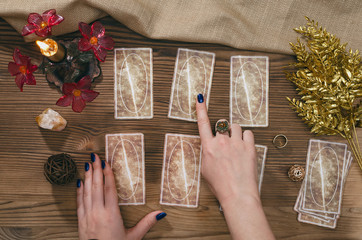 Tarot cards and hands of fortune teller on wooden table background.