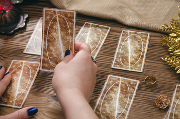 Tarot cards and hands of fortune teller on wooden table background.