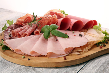 Food tray with delicious salami, pieces of sliced ham, sausage and salad. Meat platter with selection.