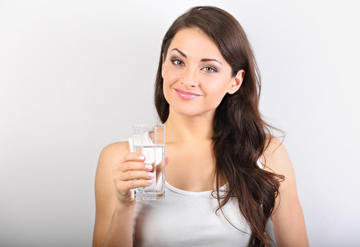 Calm happy woman with healthy skin and long curly hair drinking pure water on blue background. Closeup