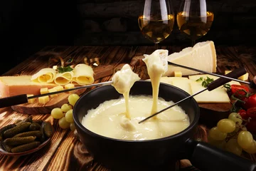 Poster Gourmet Swiss fondue dinner on a winter evening with assorted cheese © beats_