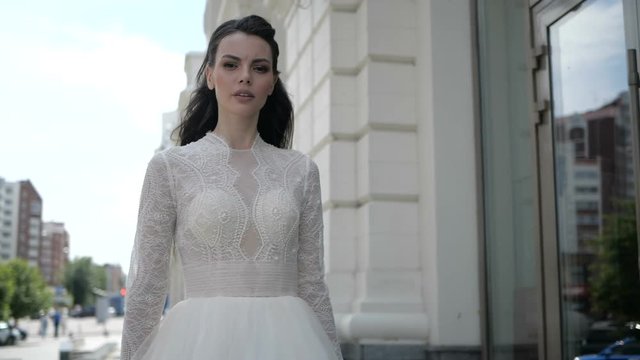 A brunnet is standing in a wedding dress