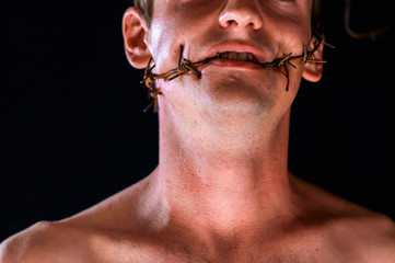 barbed wire, in the mouth, portrait on black background, blood on face