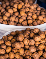 Many walnuts lie on the market and in the store. Open and peeled nuts are full of vitamins, a fresh and healthy snack for vegetarians. Shelled nuts in curved forms. Big plates on the market.