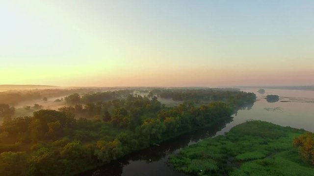 aerial view of river at sunrise 4K, Flying over the river green trees at sunrise, Very high view of the river forest at sunrise, Aerial view of mystical river at sunrise with fog
