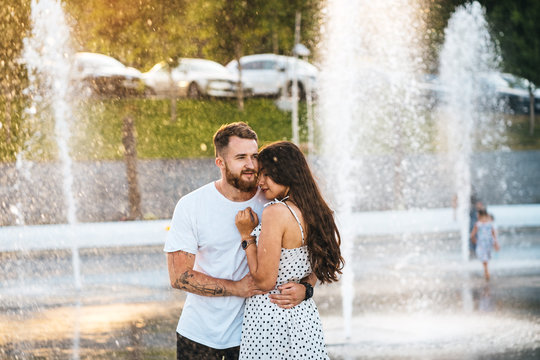 Handsome guy hugs a beautiful girl on a background of a fountain