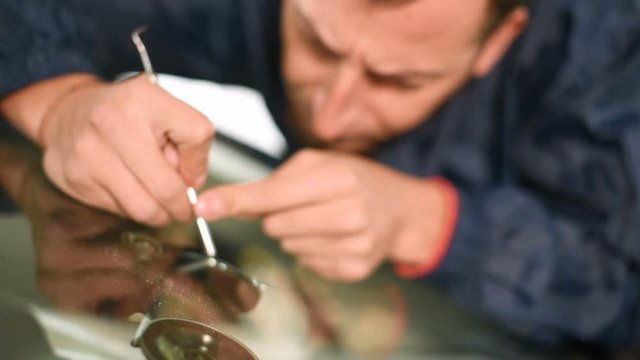 Close-up of a man professionally in the workshop engaged in eliminating cracks on the windshield of the car. Filling the crack with polymer