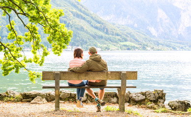 Happy couple sitting on the wooden bench - Powered by Adobe