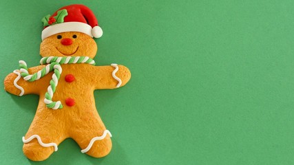 gingerbread man with red hat and buttons green and white scarf isolated on a green background with...