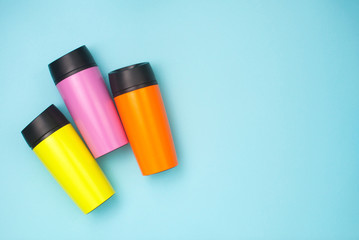 Multicolored thermo mugs on the blue background