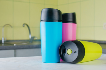 Three multicolored thermo mugs in the kitchen