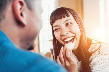 Pretty couple having fun together girl eating sweet cookies. Multiethnic young family