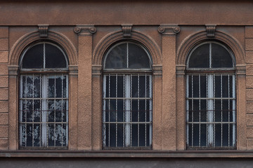 Three arched windows on an old ornate facade