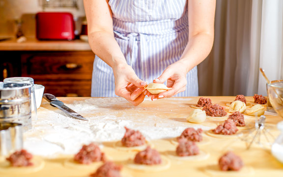 woman makes dumplings at home on kitchen table, close up