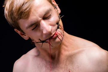barbed wire, in the mouth, portrait on black background, blood on face