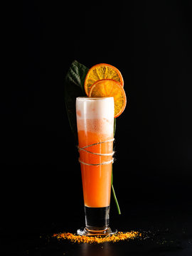 Cold Orange Cocktail In A High Glass With A Slice Of Orange. Restaurant Serve, On A Black Background.