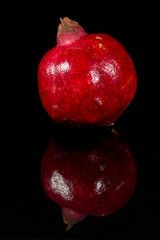 Roter Granatapfel spiegelt sich in schwarzem Glas.