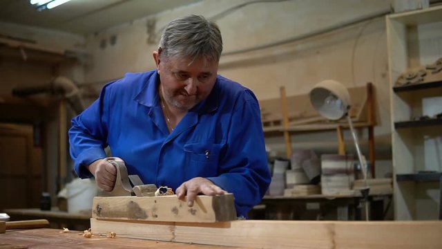 carpenter working in the Studio, worker planing a tree with a planer