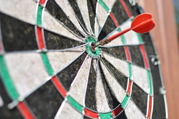 Old dart board with arrow hitting a target.