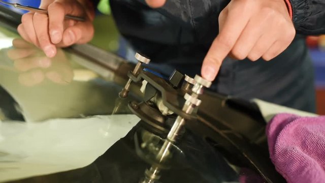 Close-up of a man professionally in the workshop engaged in eliminating cracks on the windshield of the car. Vacuum filler job