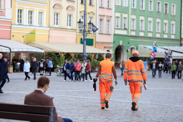 Kobieta i mężczyzna w pomarańczowych ubraniach roboczych firmy sprzątającej miasto.