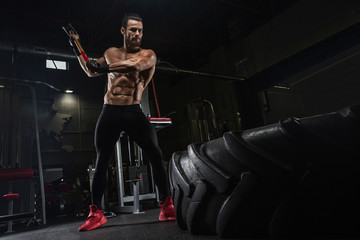 Fototapeta na wymiar Young handsome athlete bodybuilder, weightlifter, doing crossfit, with a sledgehammer, in a modern gym. Concept-strength, beauty, power, sport, health, sports nutrition, diet, styroydy, scales.