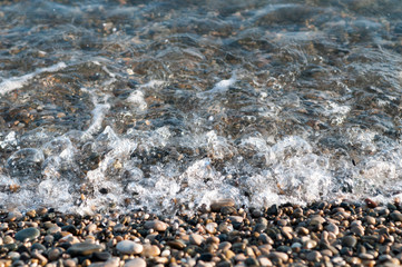 pebble stones by the sea. Silky waves of blue sea from long exposure.