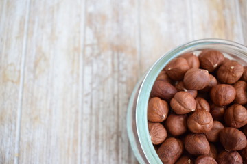 Obraz premium Hazelnuts in a glass jar in the background of the tree. Copy space.