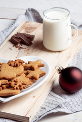 Cup of milk and gingerbread cookies on a wooden board