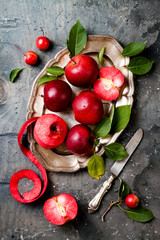 Still life with apples on vintage plate over gray table, top view. Fresh red apples Baya Marisa with leaves.