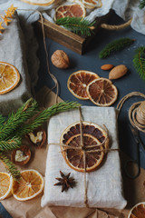 Christmas or New Year composition with handmade gifts, dry oranges, cinnamon, fir tree on dark stone table. Holidays preparations, hugge concept, selective focus
