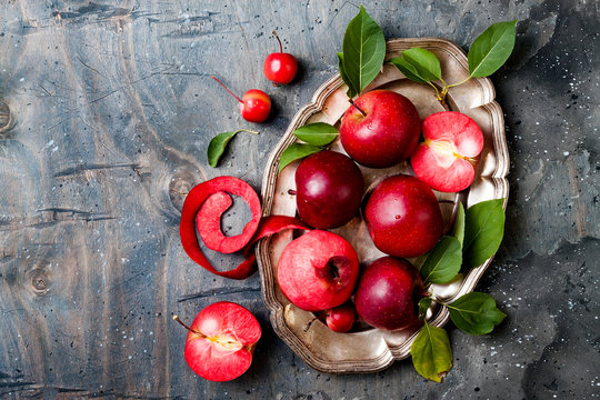Still life with apples on vintage plate over gray table, top view, copy space. Fresh red apples Baya Marisa with leaves.