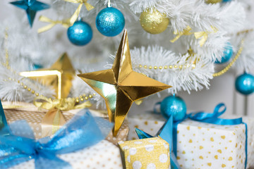 family holiday concept. Merry Christmas and Happy Holidays. Studio with Christmas decor. Winter home decor. Christmas tree, fireplace with firewood Boxes with gifts and golden and blue bows. Xmas