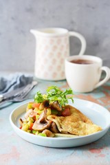 Homemade omelet with mushrooms, vegetables and arugula on a plate. Wonderful healthy breakfast.