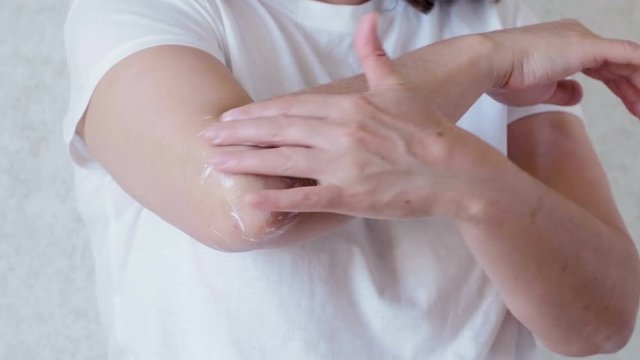Woman rubs cream elbow. joint pain. cosmetic procedures