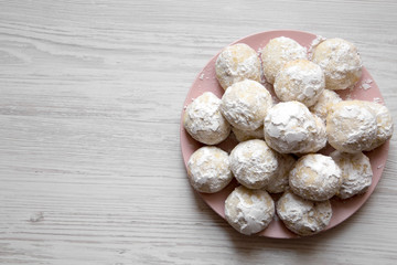 Homemade white mexican wedding cookies on pink plate over white wooden background, top view. Copy space.