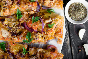 Delicious and appetizing pizza from yeast dough. Delicious and healthy vegetable pizza. Vegetable pizza on a black wooden table.