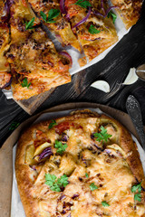 Delicious and appetizing pizza from yeast dough. Delicious and healthy vegetable pizza. Vegetable pizza on a black wooden table.