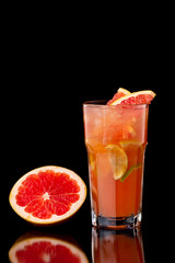 Closeup glass of citrus fresh juice with grapefruit, lime and lemon isolated at black background.