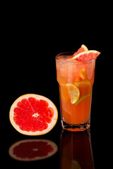 Closeup glass of citrus fresh juice with grapefruit, lime and lemon isolated at black background.