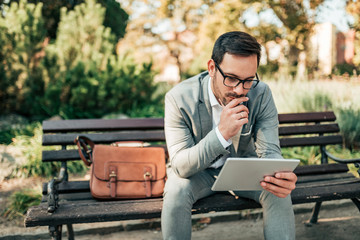 Fototapeta premium Young businessman working on tablet outdoors.