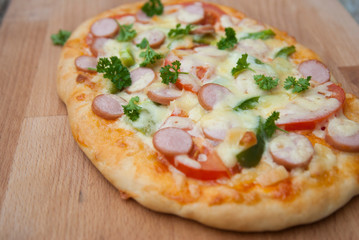 Fresh baked homemade pizza with cheese and tomatoes over wooden cutting board. Rustic style.
