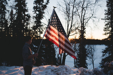 Boy looking out on frozen lake with flag