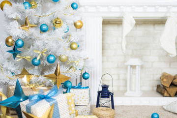 family holiday concept. Merry Christmas and Happy Holidays. Studio with Christmas decor. Winter home decor. Christmas tree, fireplace with firewood Boxes with gifts and golden and blue bows. Xmas