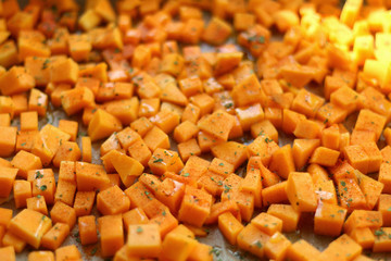 Sliced butternut squash garnished with spices, herbs and olive oil, ready for roasting. Selective focus.
