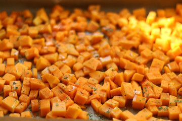 Sliced butternut squash garnished with spices, herbs and olive oil, ready for roasting. Selective...