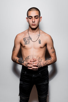 Tattooed shirtless young man portrait isolated over white wall