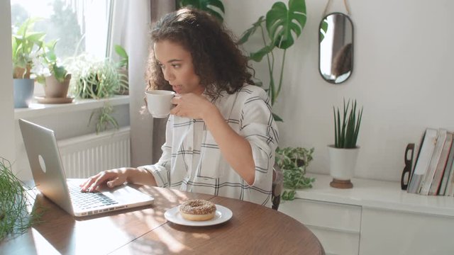 Charming young woman typing on laptop computer at home.